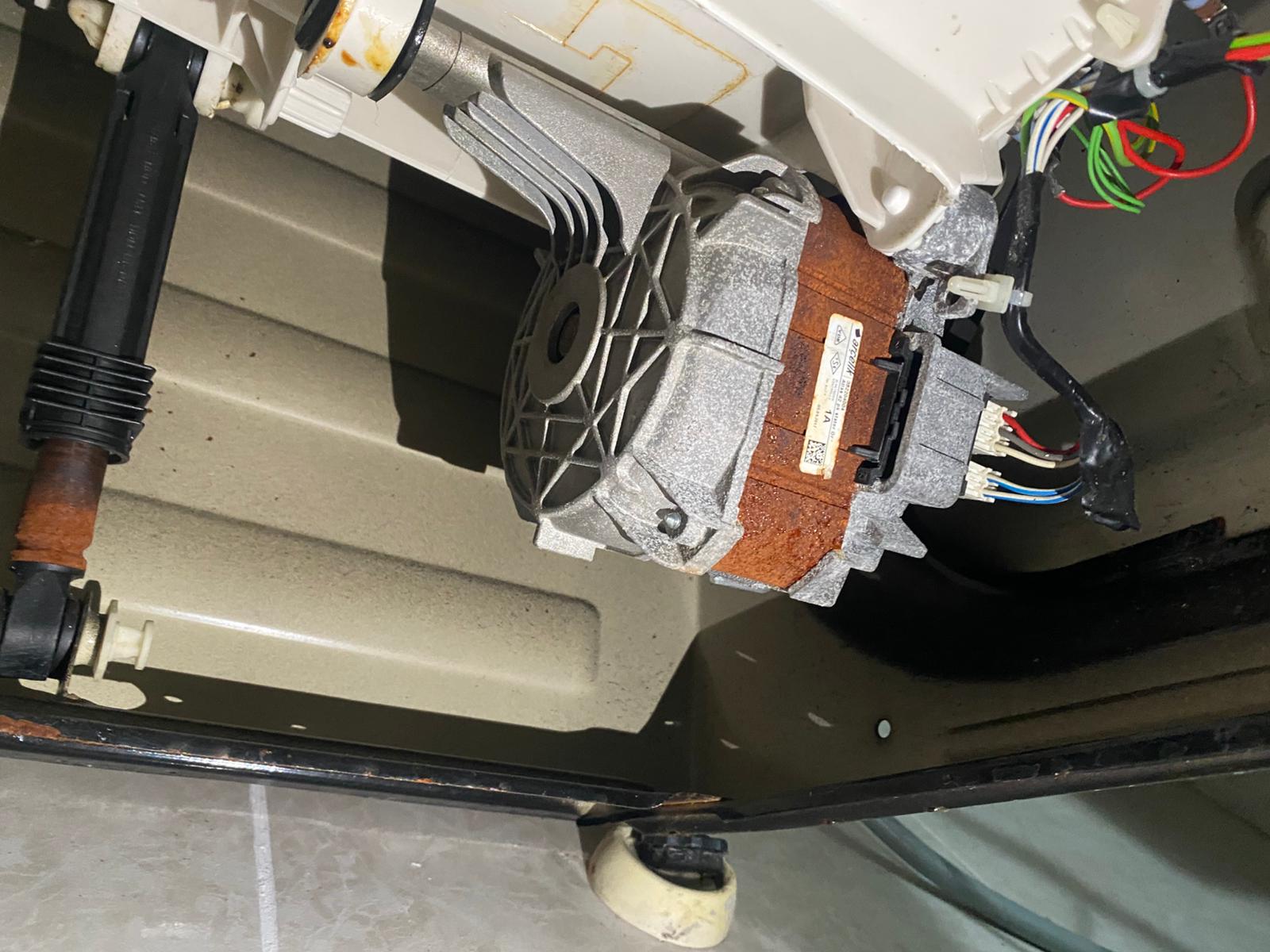 Gerçek çamaşır makinesi teknik servis çalışması — motor ve alt aksam incelemesi.